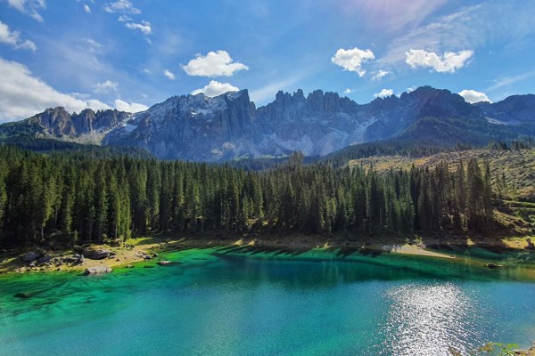 Summery mountain panorama with mountain range, pine forest and turquoise lake