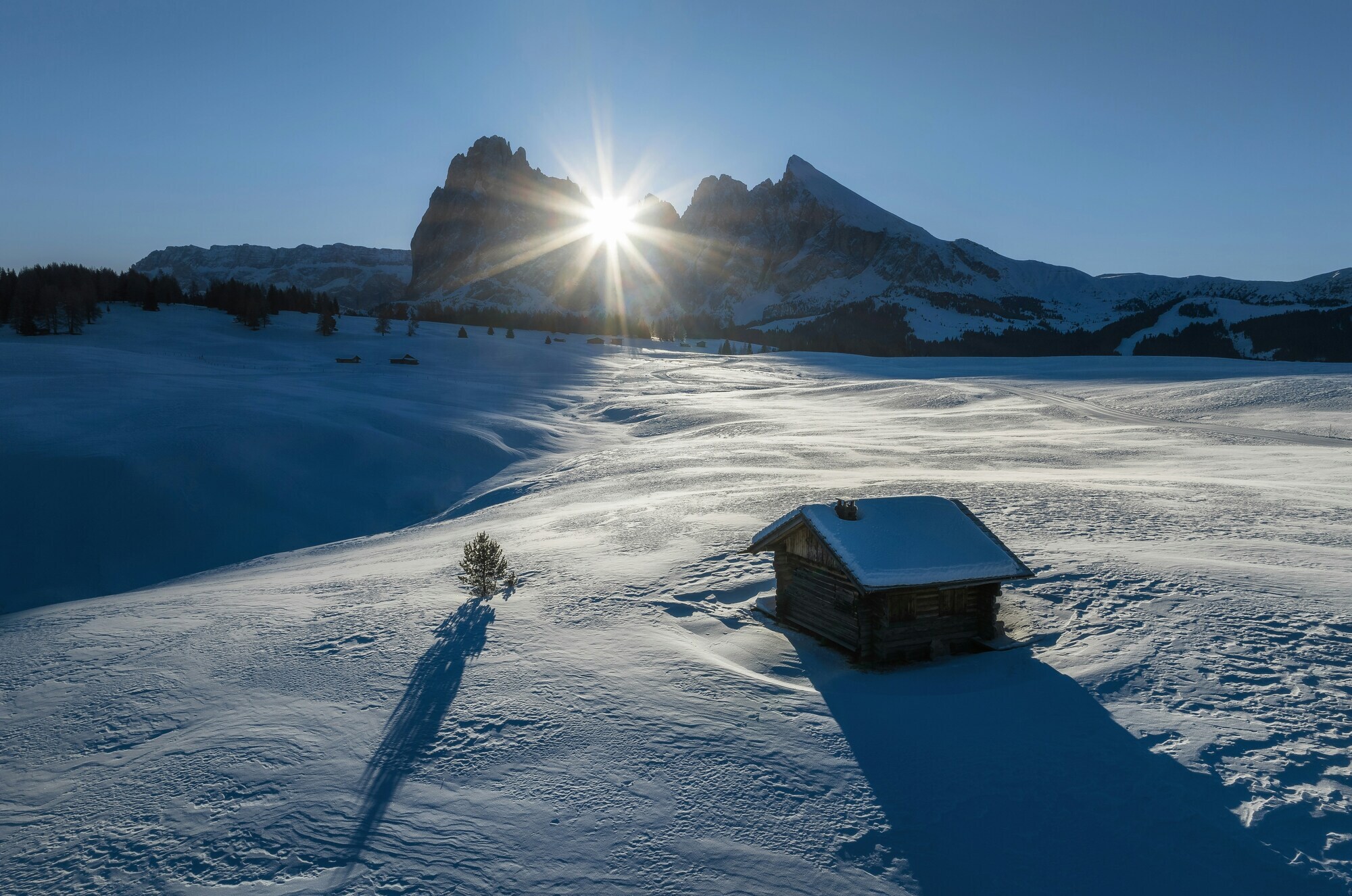 Sun shines through mountain peaks onto the snow-covered landscape