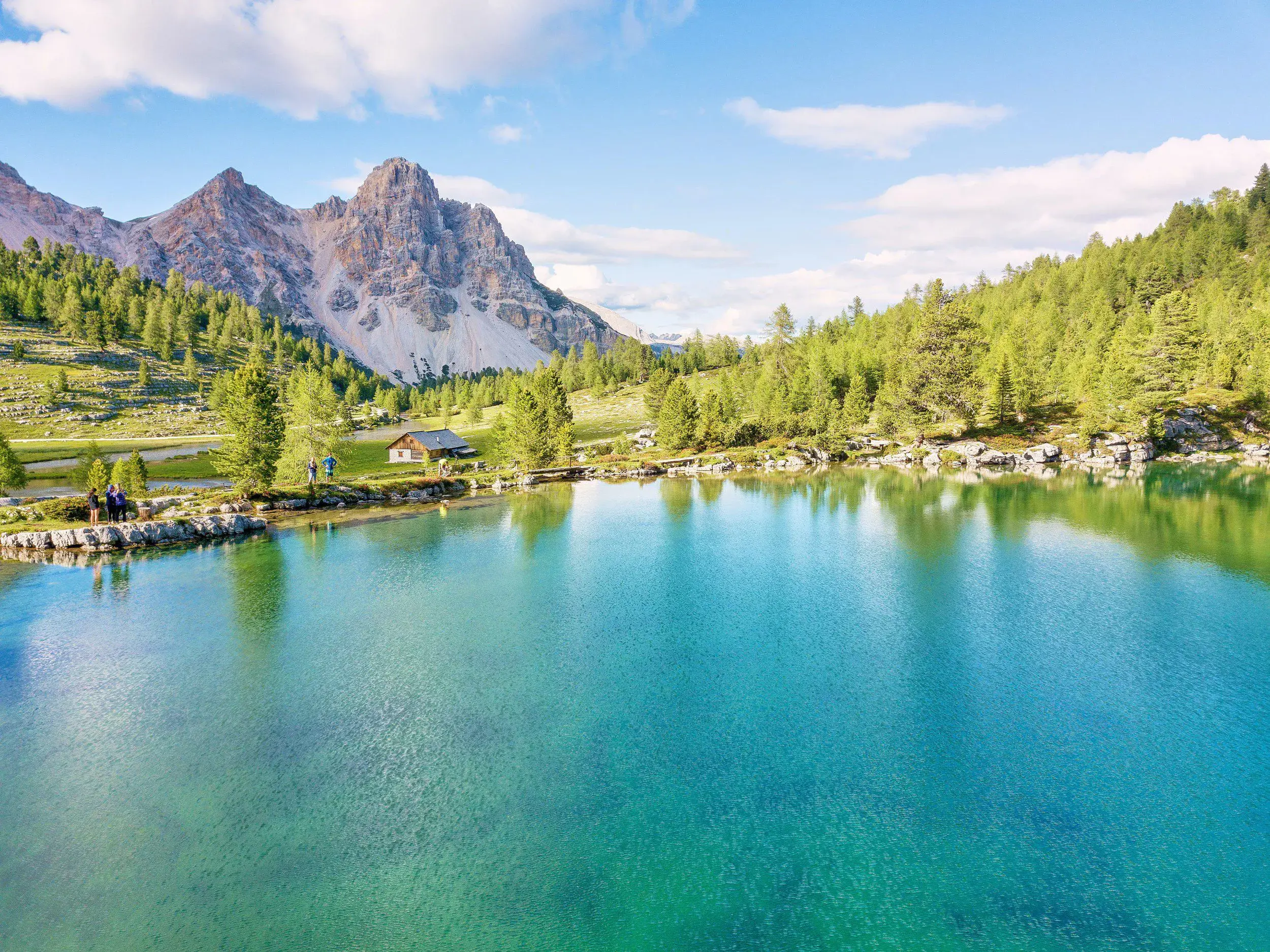 Lé Vert lake at Fanes pasture with green waters, hikers, hut & mountains