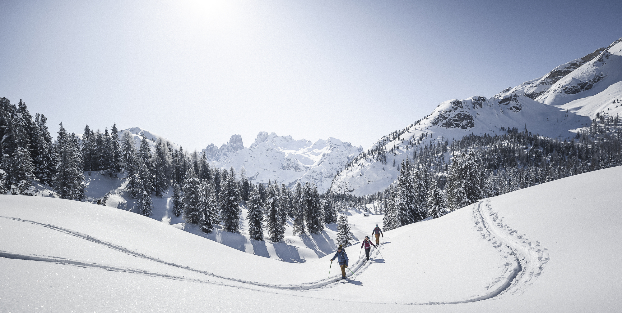 People with touring skis in a snow-covered landscape