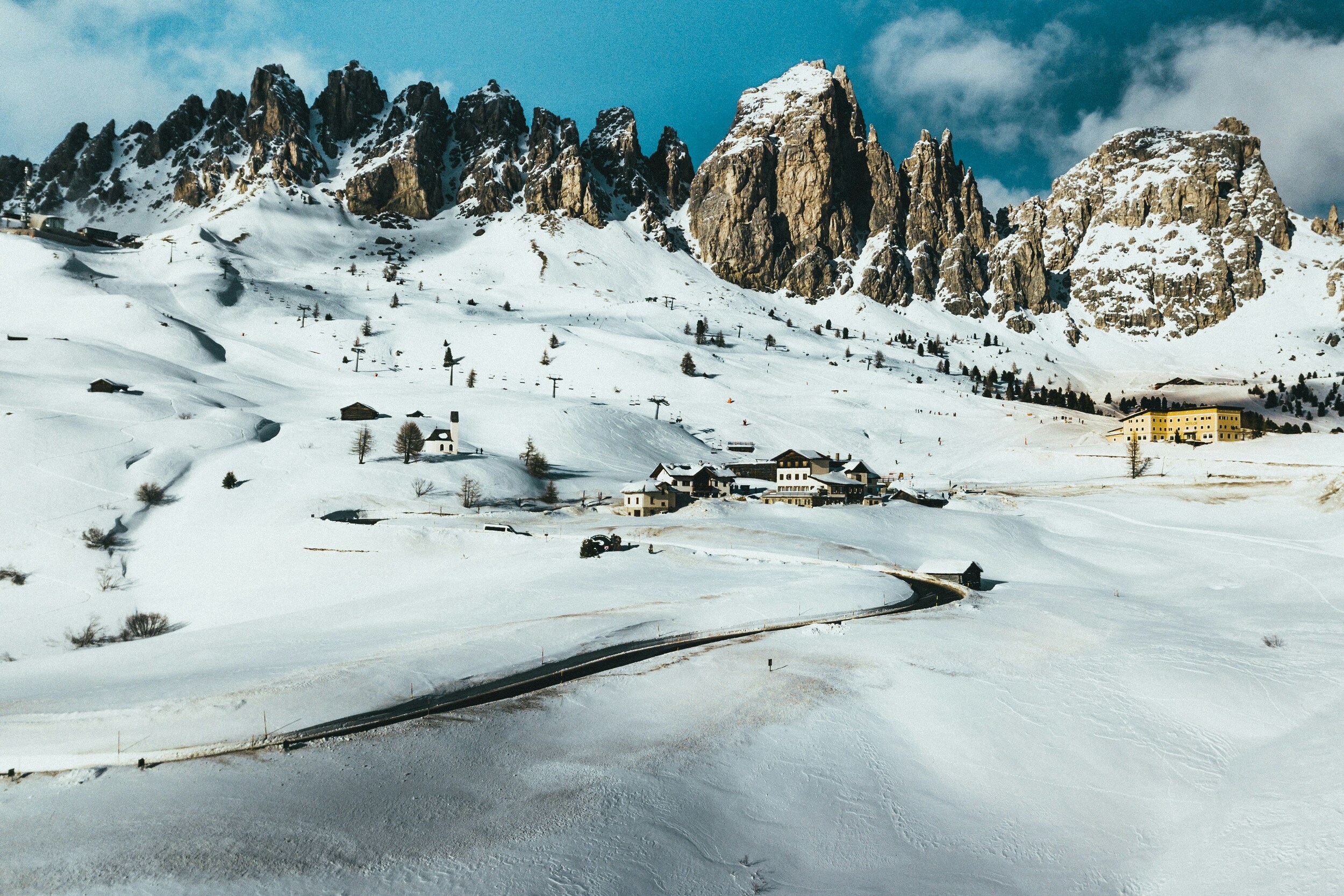 Mountain pass road in winter, with peaks and houses in the snow