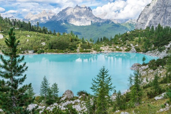 Turquoise blue lake framed by trees, rocks and mountains