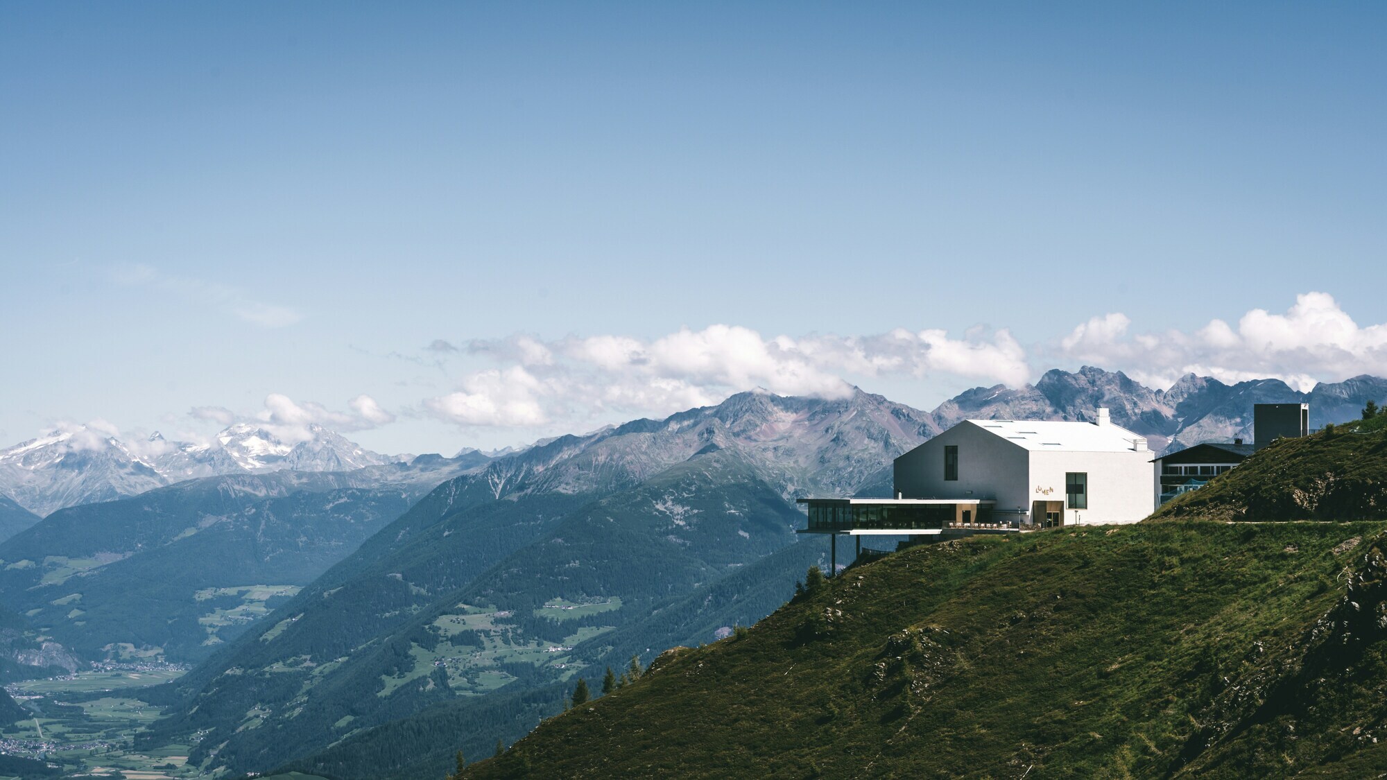 Modern white building on the side of a mountain, mountains and valleys in the background