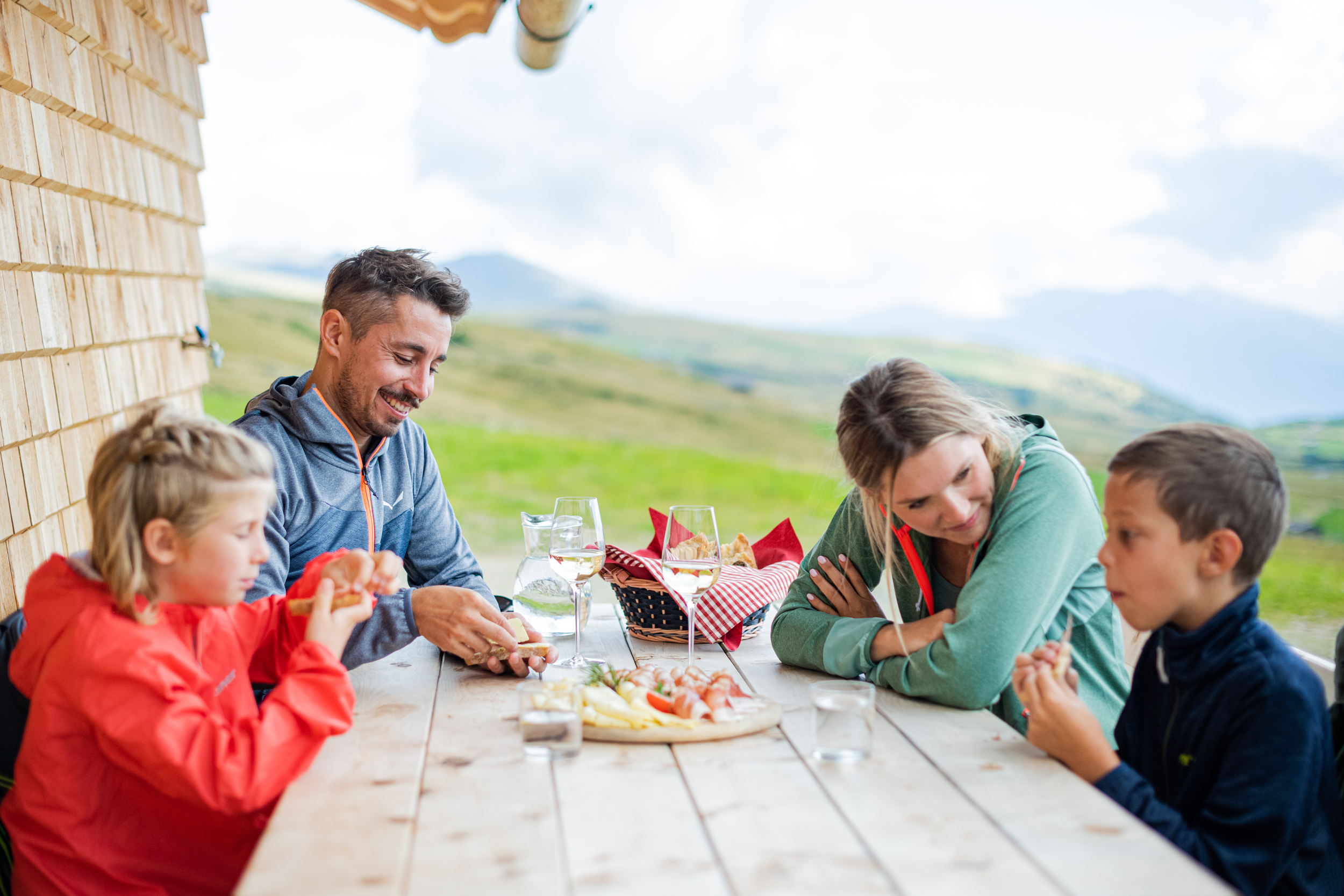 Family eating and drinking on a wooden table outdoors