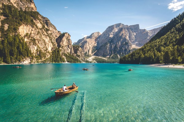 A few rewing boats on a turquoise lake surrounded by mountains