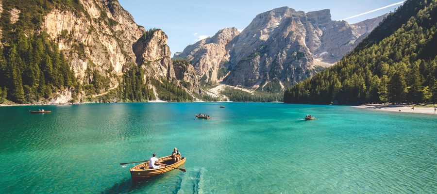 A few rewing boats on a turquoise lake surrounded by mountains