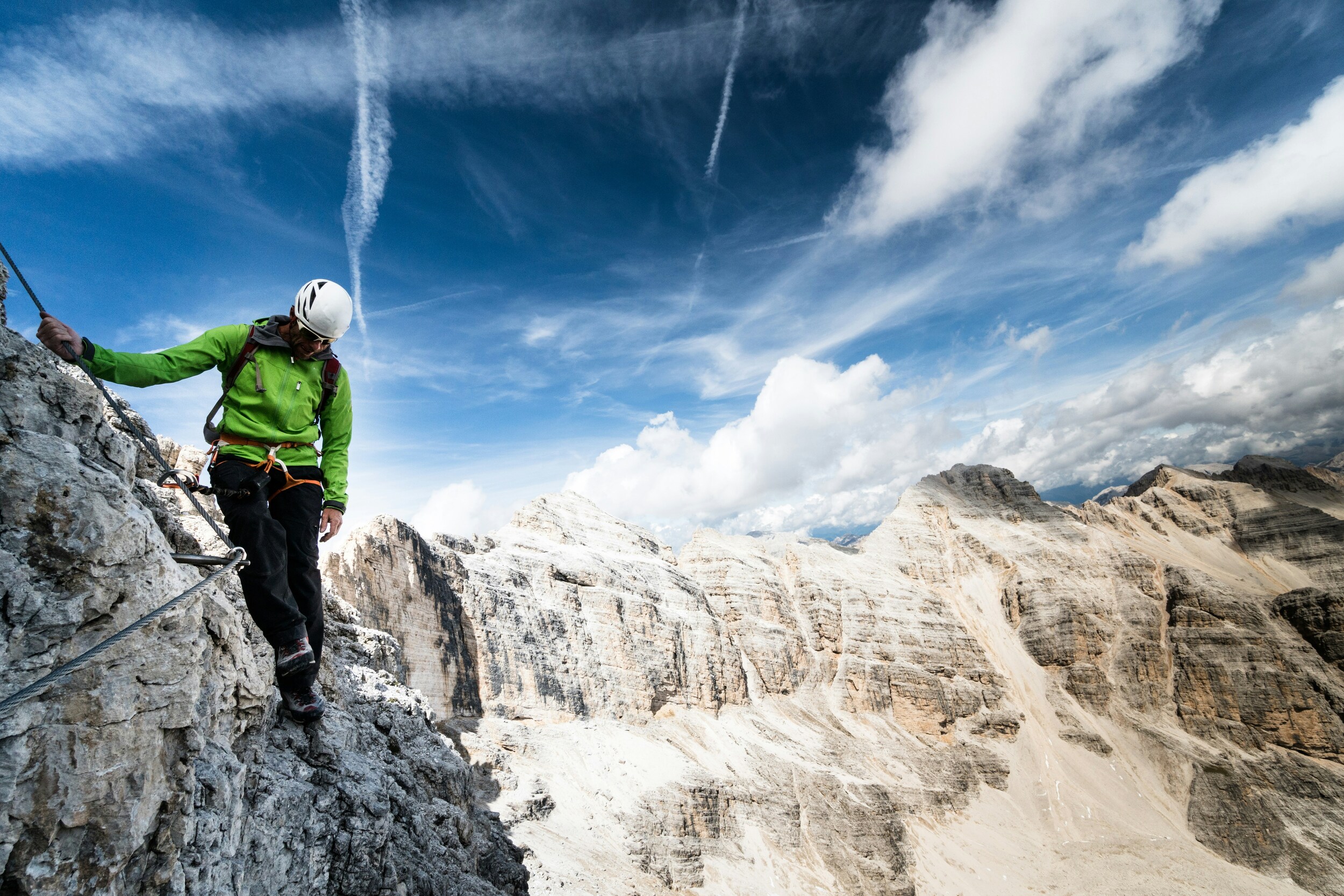 Climber on an exposed fixed rope route in the middle of the mountains