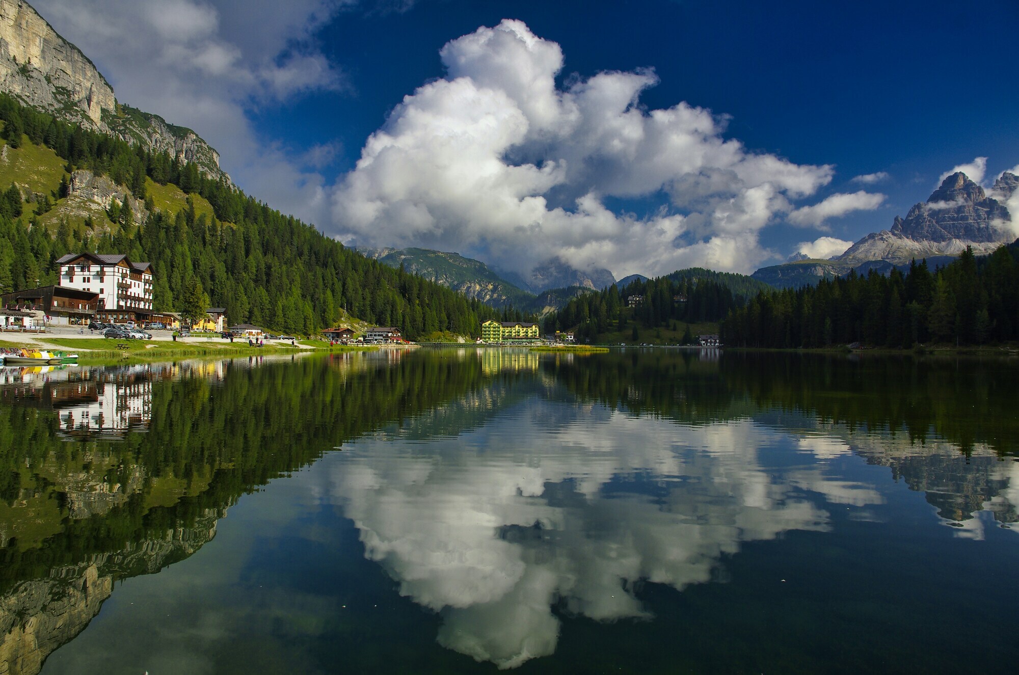 Houses, clouds, trees and mountains reflected in a lake