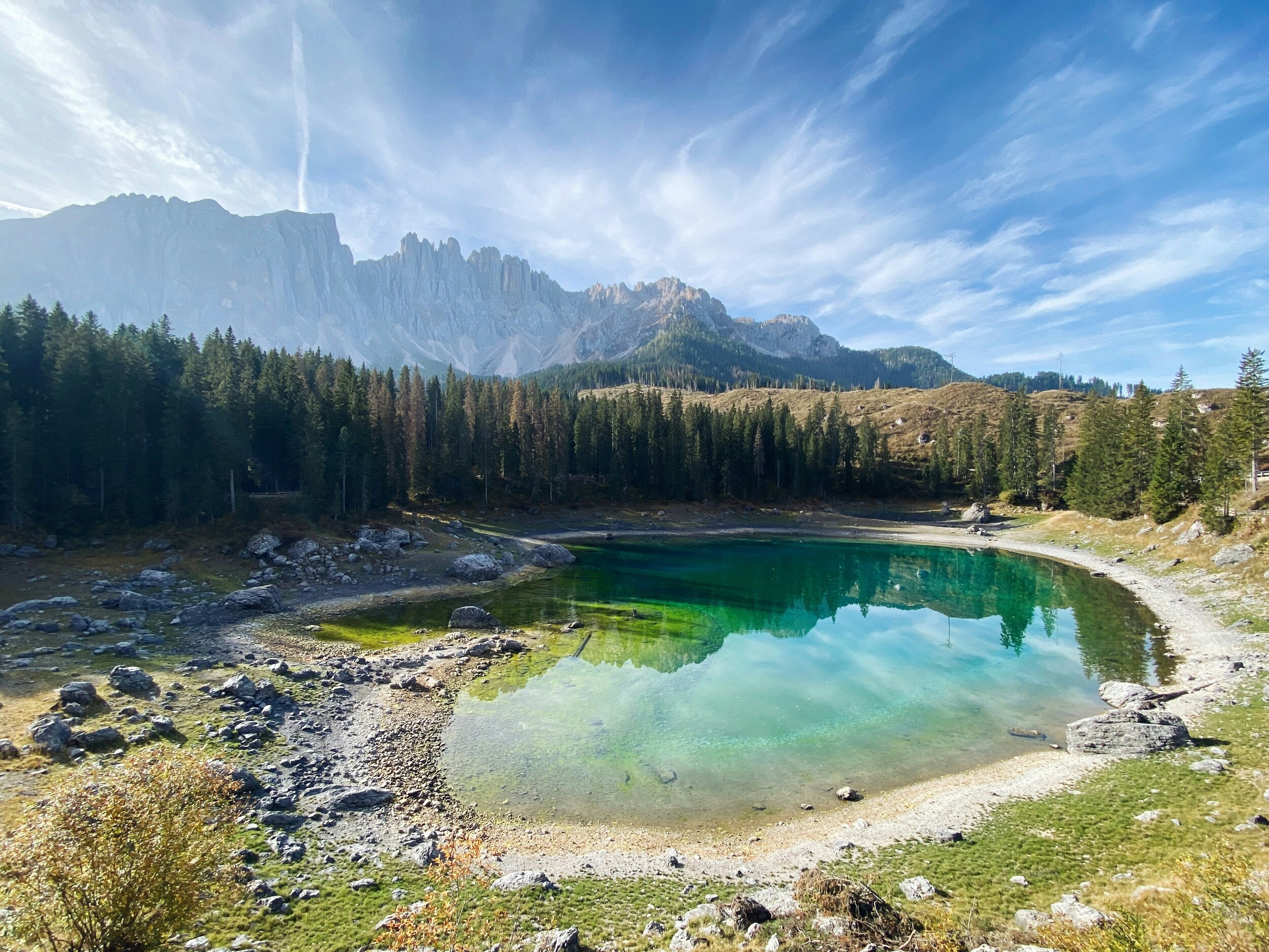 Lake with blue-green water framed by conifers, mountain range in the background