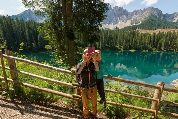 Couple taking a selfie with a turquoise lake and mountain landscape in the background