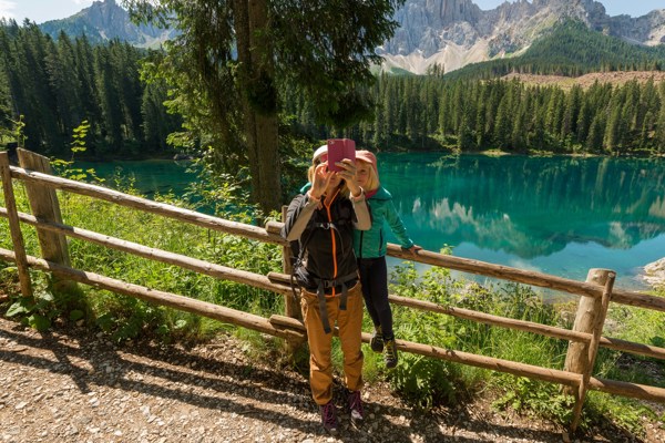 Couple taking a selfie with a turquoise lake and mountain landscape in the background