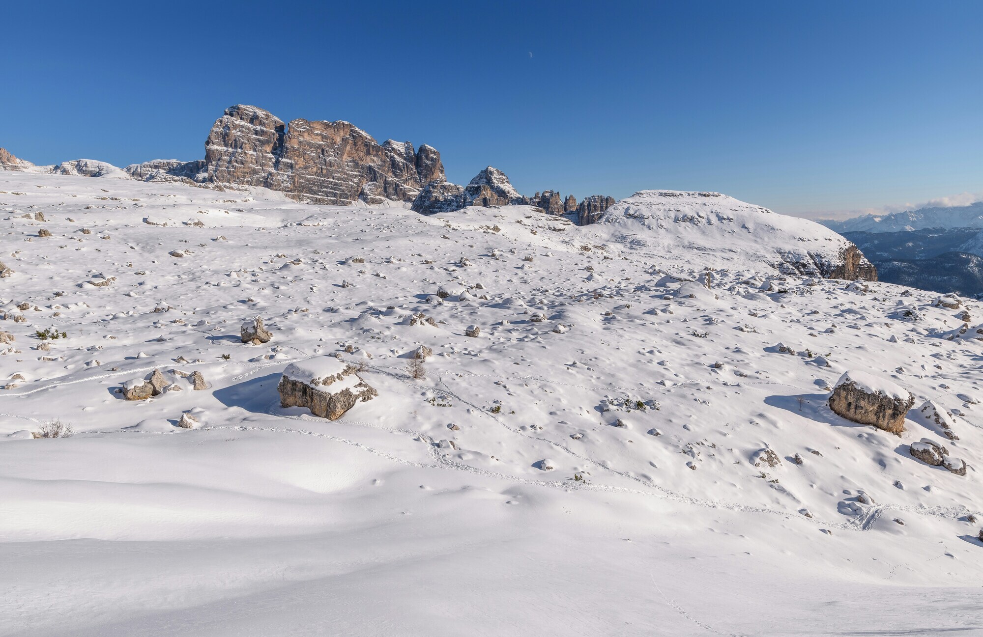 Snow-covered plain with single rocks and mountains