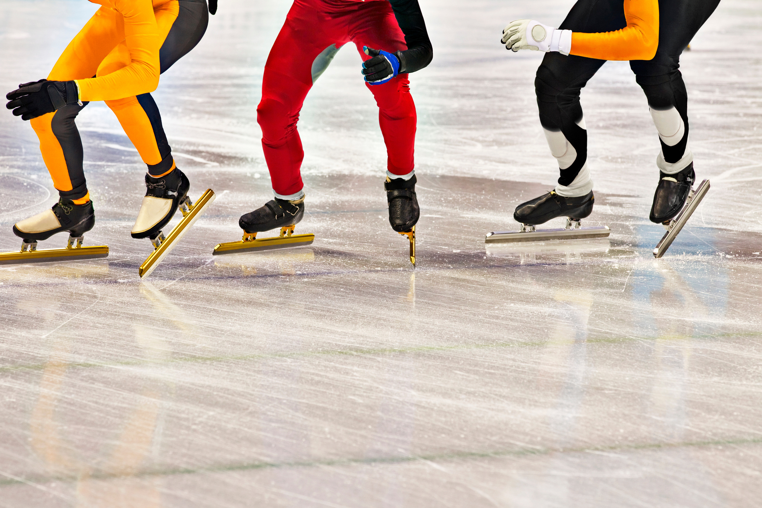 3 speed skaters in starting position on the ice, visible up to the waist