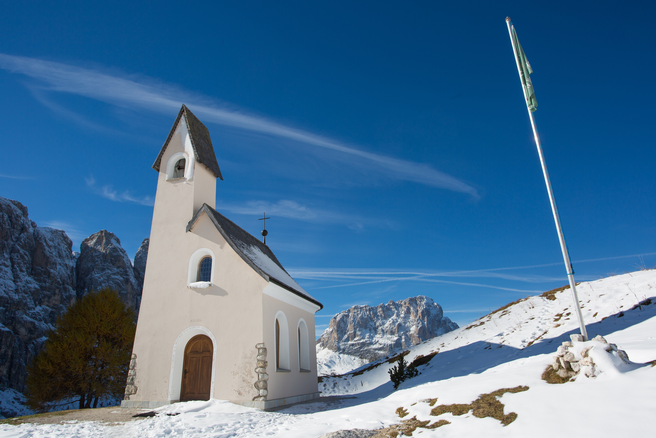 Small church and flagpole in the snow in the mountains