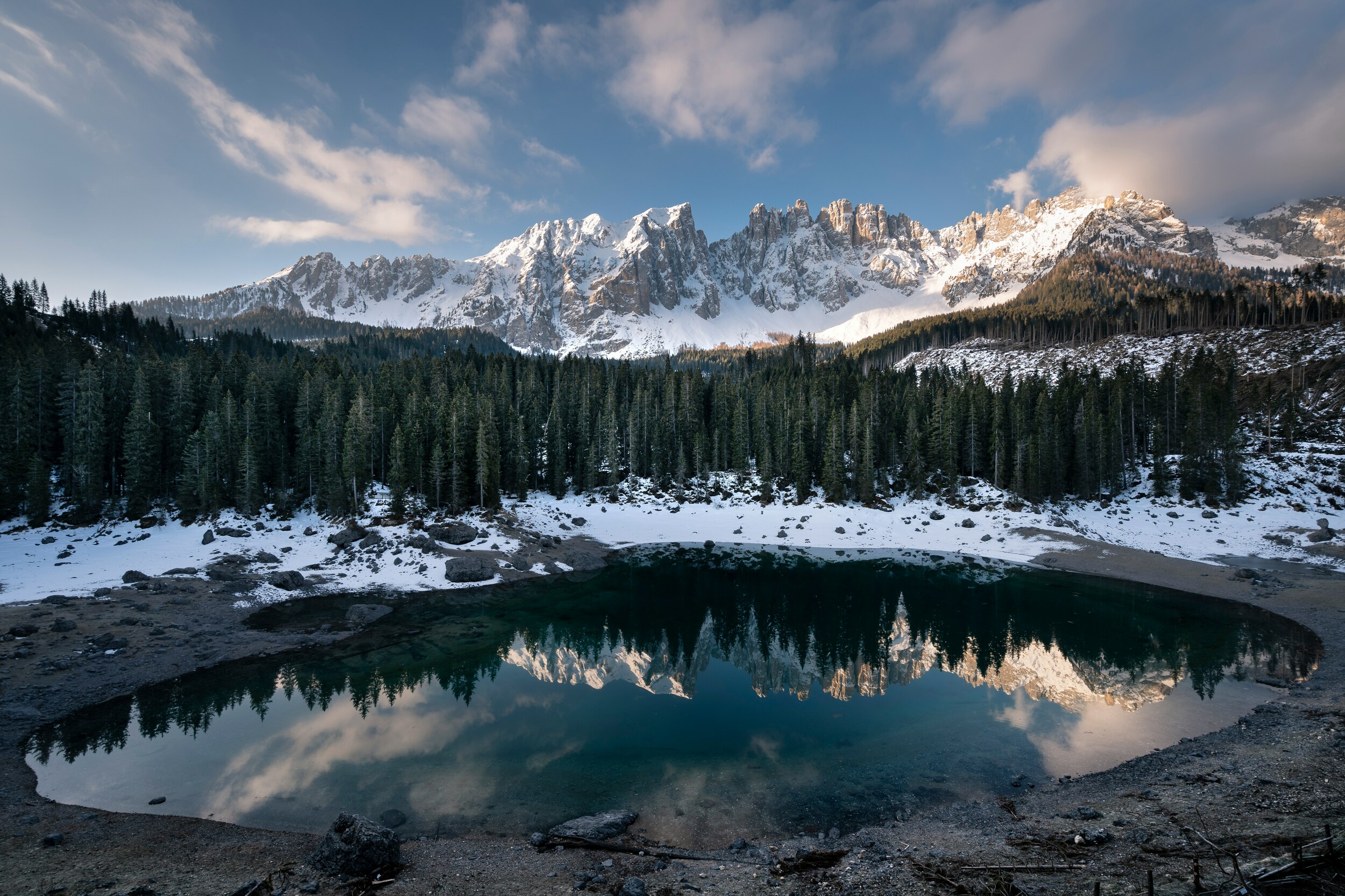 Dark winter landscape with trees and mountain range reflected in a mountain lake