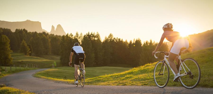 2 persons with road bikes on an asphalted road at sunset in nature