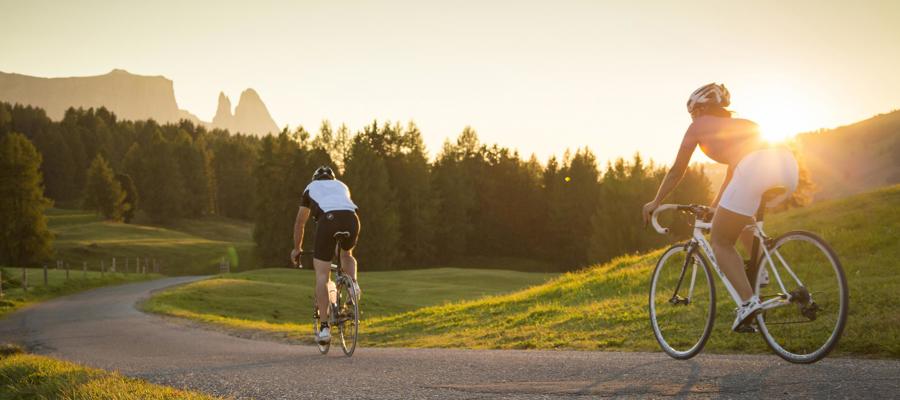 2 persons with road bikes on an asphalted road at sunset in nature