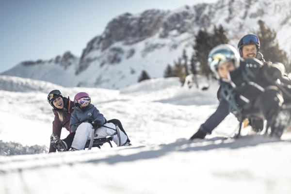 Family with kids on sleighs on a toboggan run