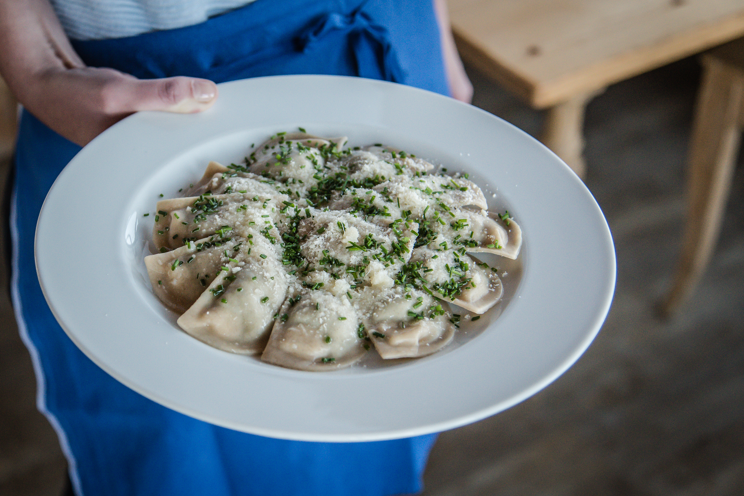 Filled dumplings served on a plate covered with parmesan and chives