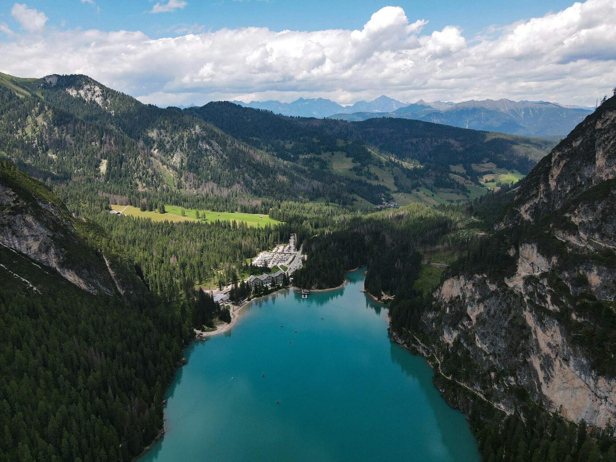 View of a mountain lake from an elevated point, framed by wooded mountain slopes