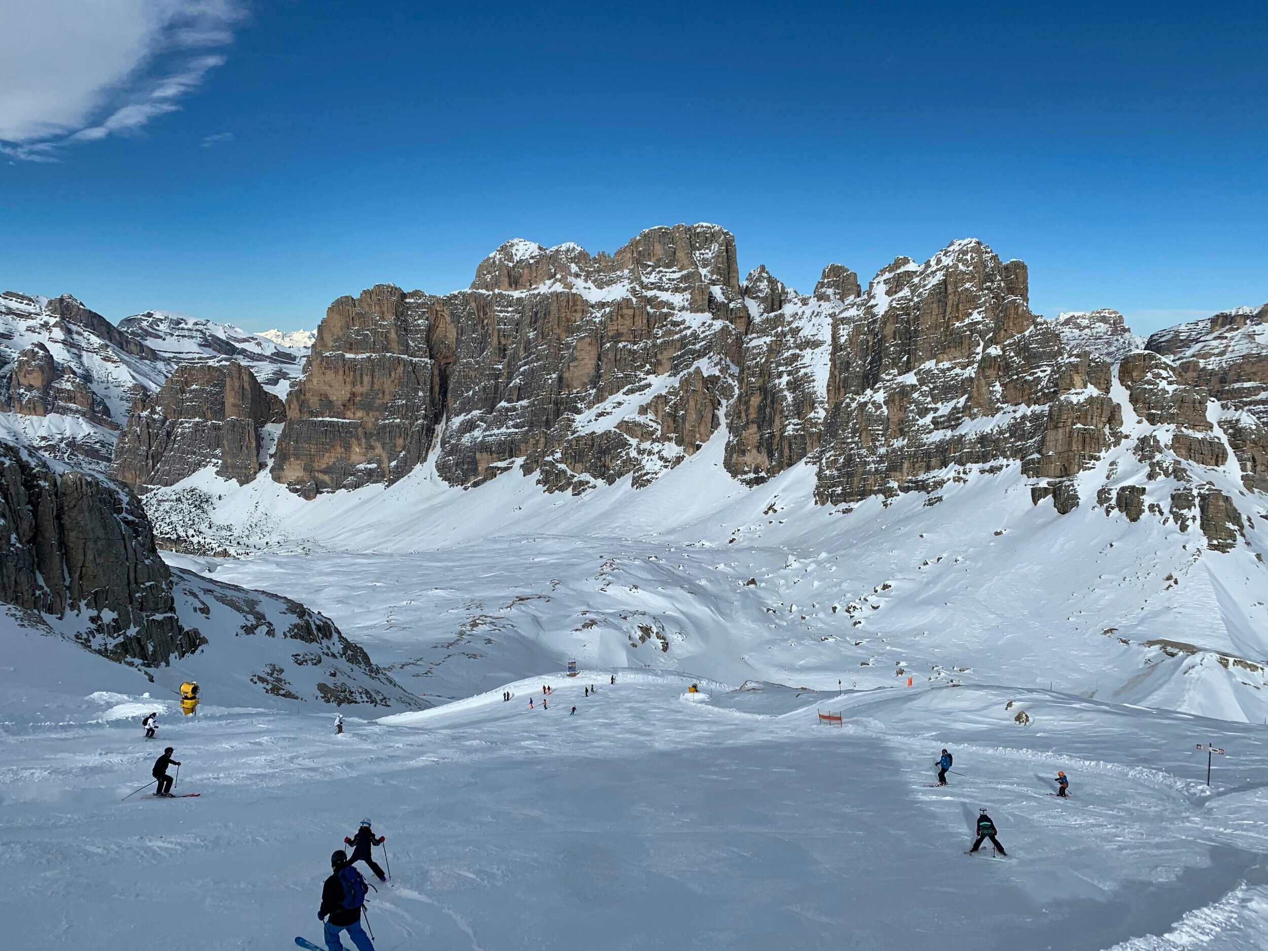 Skiers on a prepared ski slope with mountains in the background