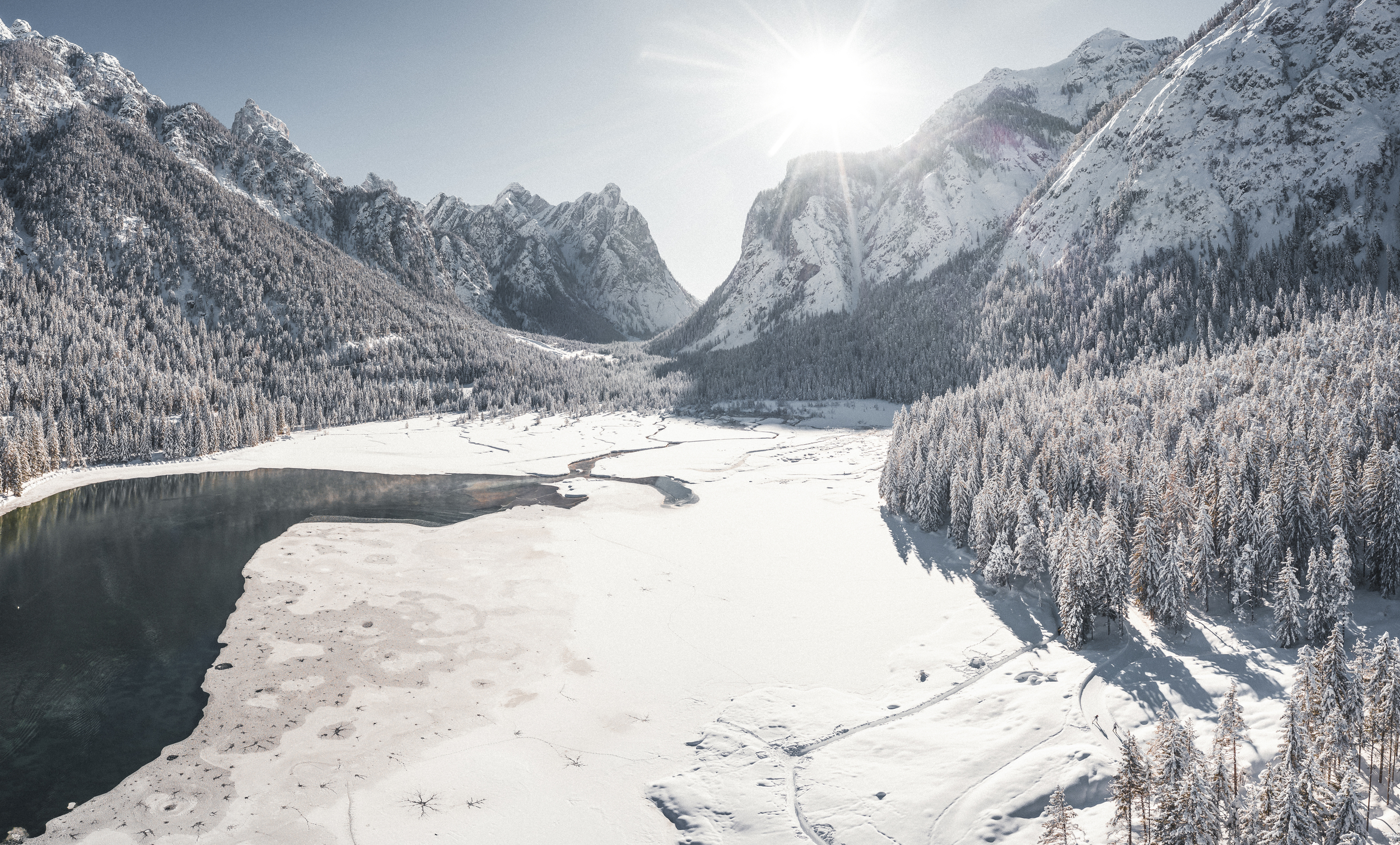 Lake in the middle of the mountains in winter, partly frozen and snow-covered