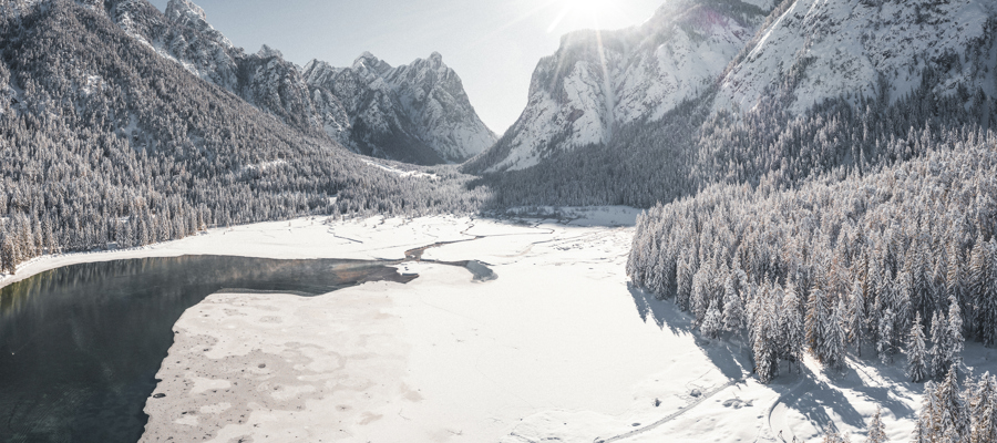 Lake in the middle of the mountains in winter, partly frozen and snow-covered