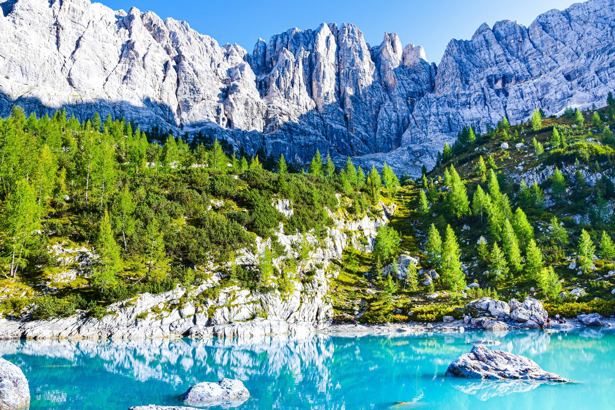 Tourquise blue lake framed by rocks, trees and peaks