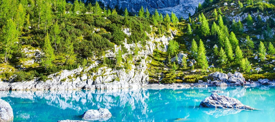 Tourquise blue lake framed by rocks, trees and peaks