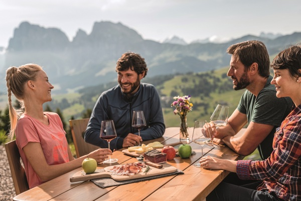 3 men and a women sitting at a table, drinking and eating