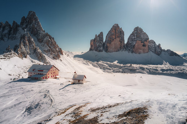 Hut and small church in a snowy landscape surrounded by Dolomites peaks