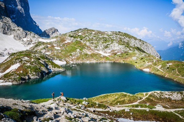 Hikers on the shore of a crystal-blue mountain lake