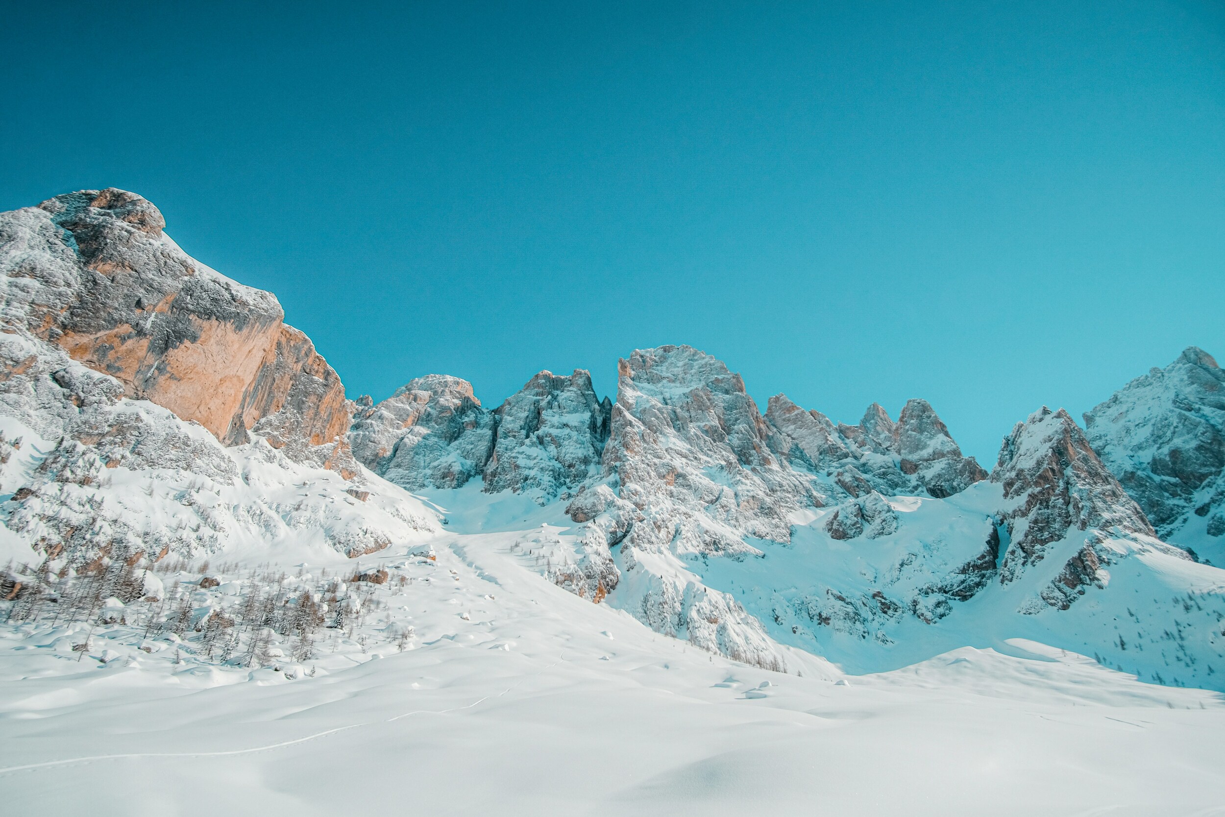 Snow-covered valley, with woods, peaks and blue sky