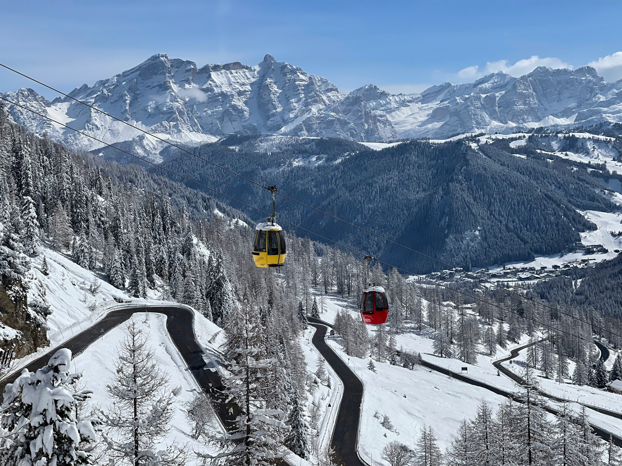 One red and one yellow cable car cabin in a winter-white mountain landscape