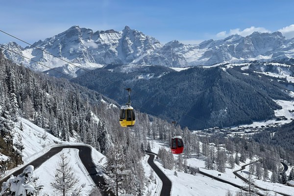 One red and one yellow cable car cabin in a winter-white mountain landscape