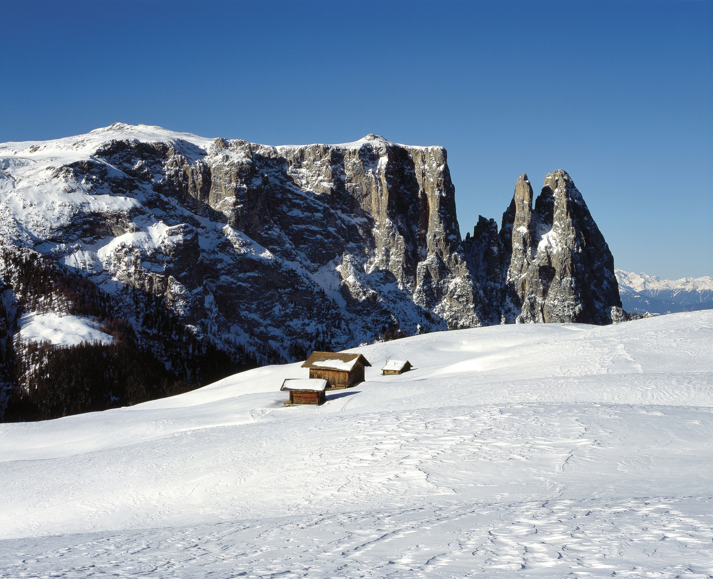 Small huts on a snowy plain with mountains in the background