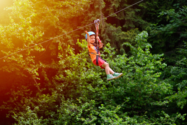 Child with helmet on zip wire between trees