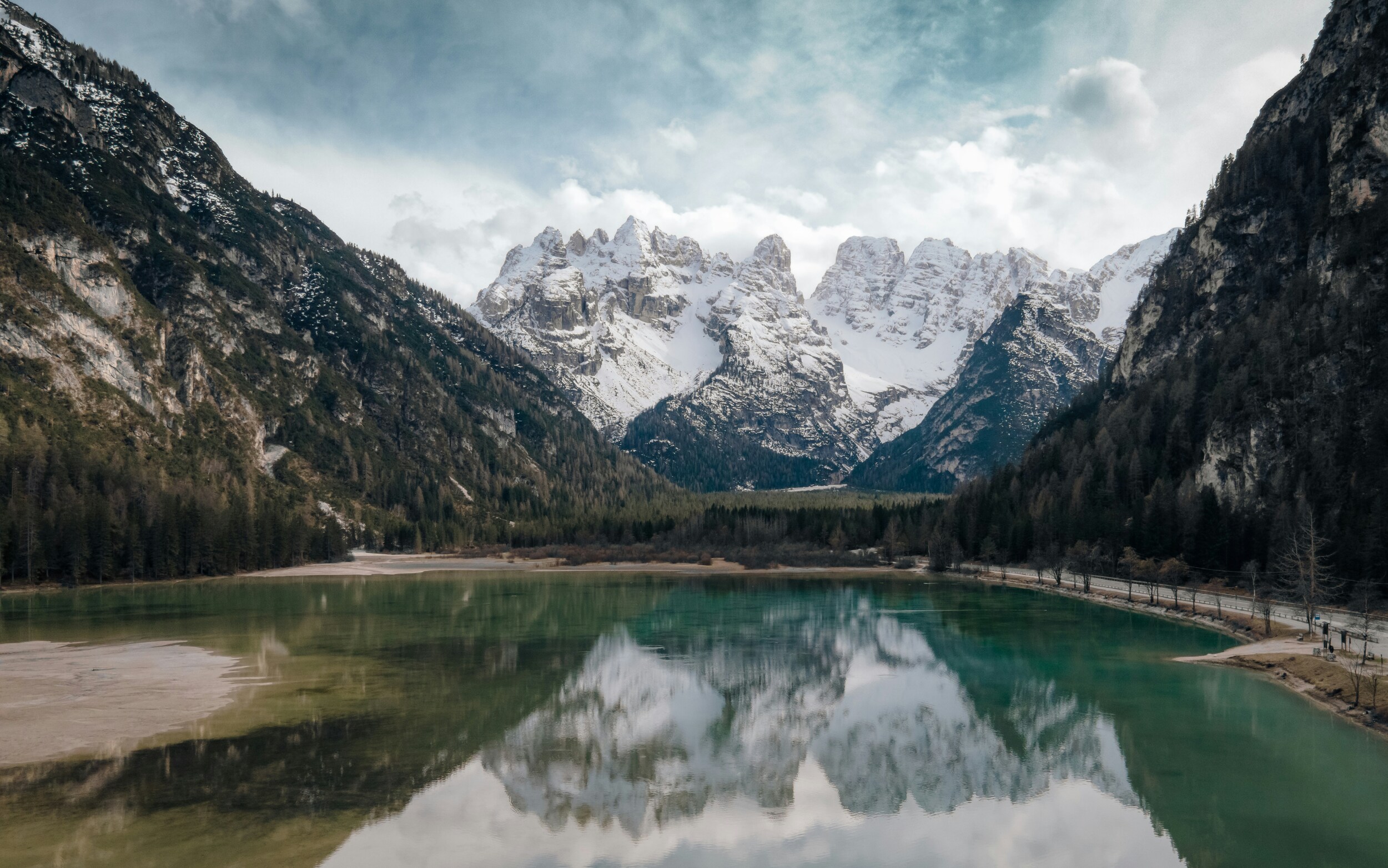 Snow-covered peaks reflected in a green mountain lake