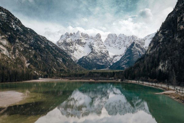 Snow-covered peaks reflected in a green mountain lake