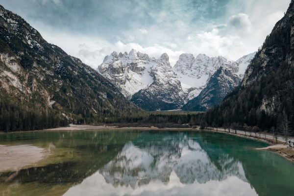 Snow-covered peaks reflected in a green mountain lake