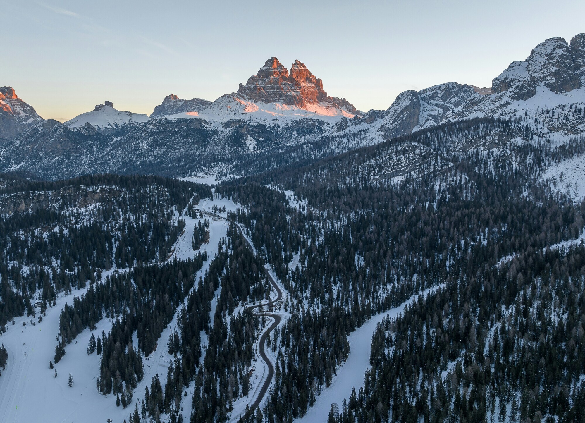 Pass road, snow-covered woods and peaks at sunrise