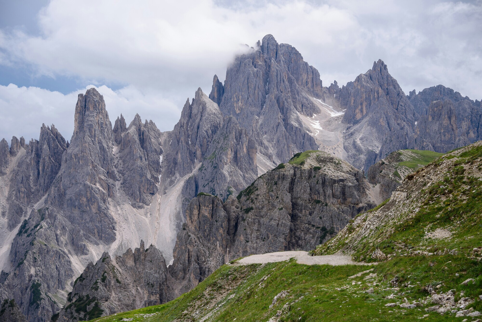 Rugged mountain peaks an dgreen hills with cloudy sky