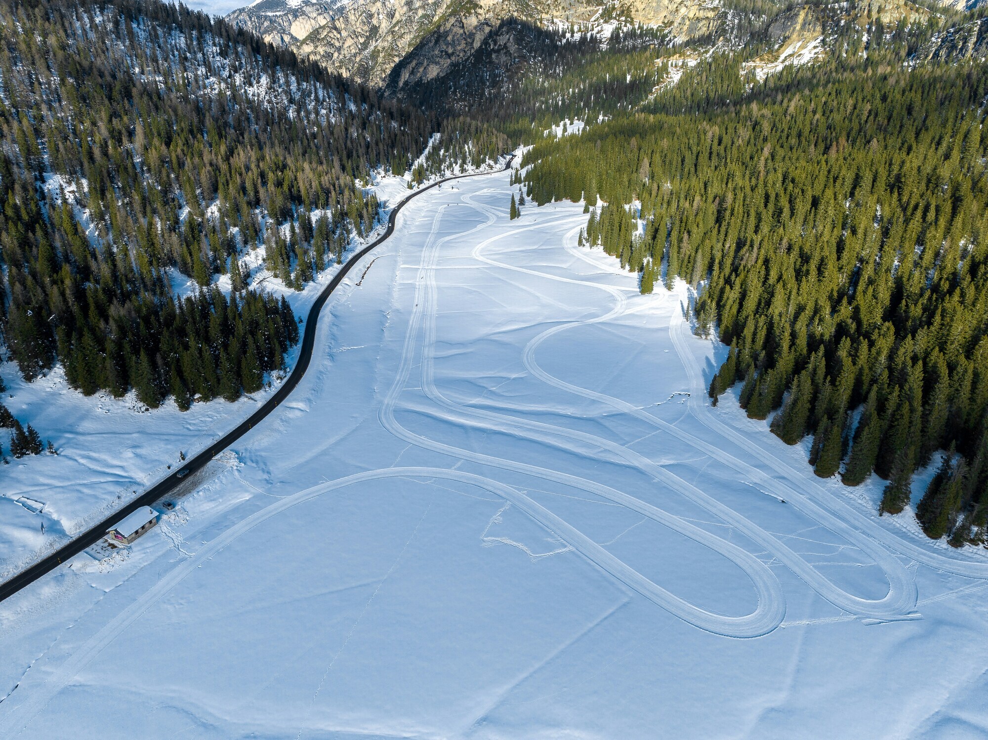 Winding cross-country ski run with framed by trees and a street, seen from above