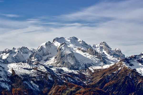 Snow-covered peak with golden autumn trees down in the valley