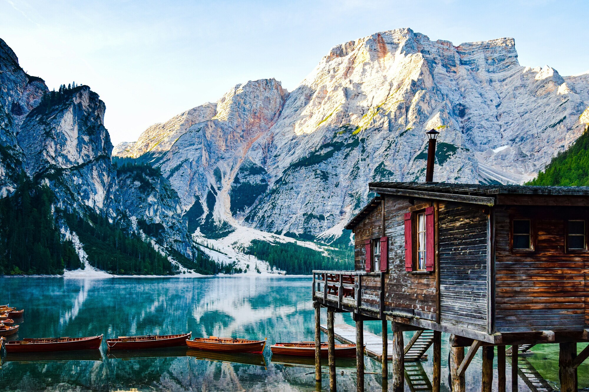 Wooden house on stilts and boats on the shore of a lake, mountain giant in the background