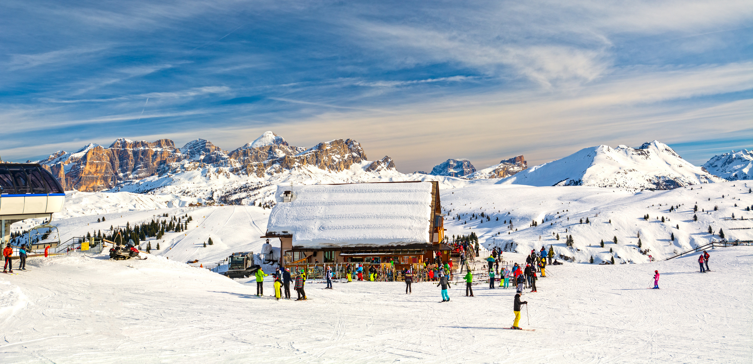 Ski hut with skiers and ski run in the snow-covered mountains