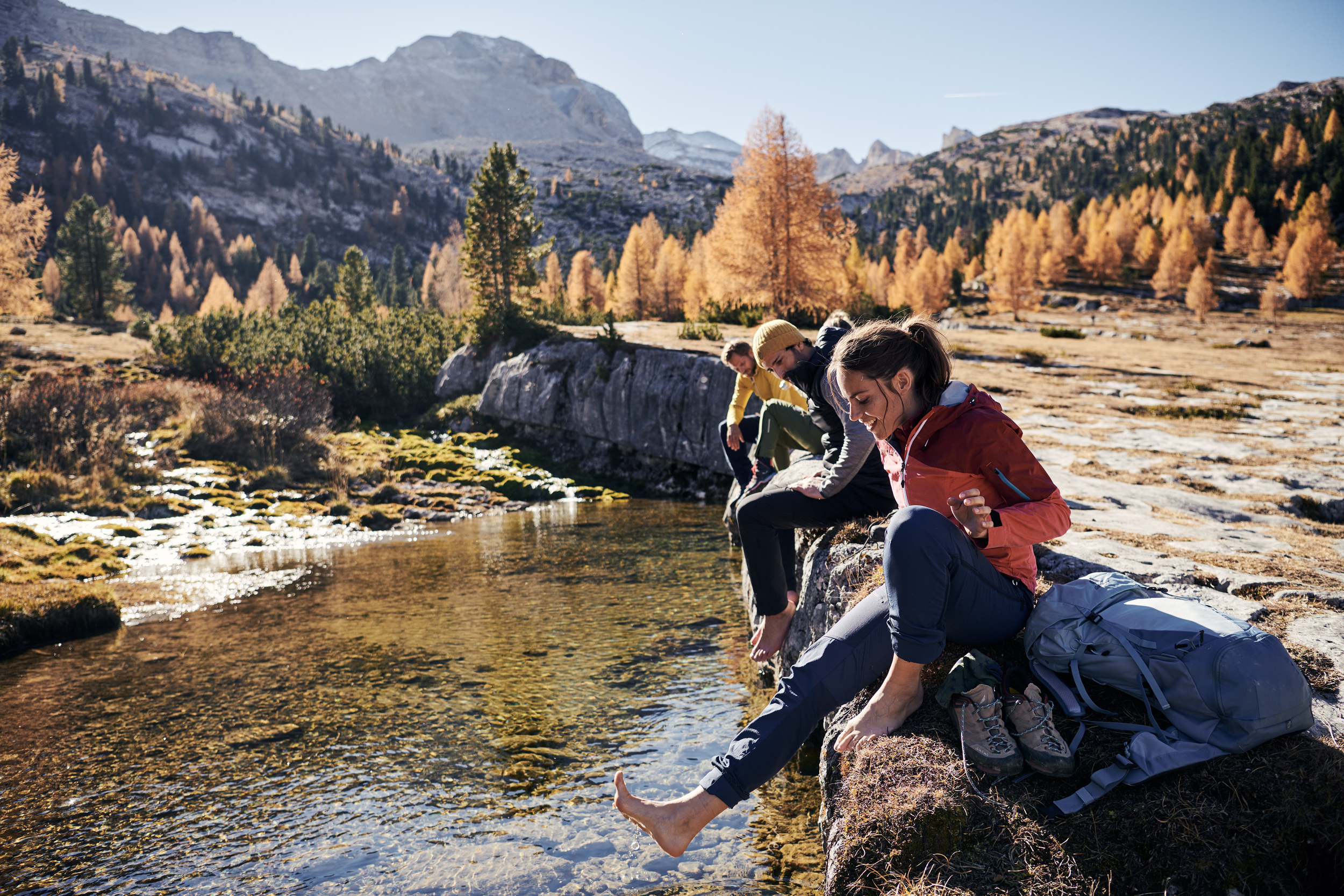 Autumnal mountain scenery, hikers dip their feet in a small lake