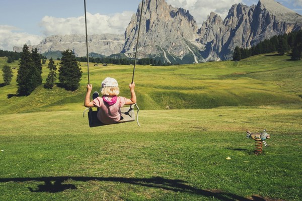 Child on a swing in the middle of a mountain landscape