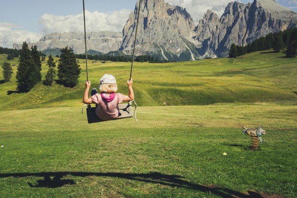 Child on a swing in the middle of a mountain landscape