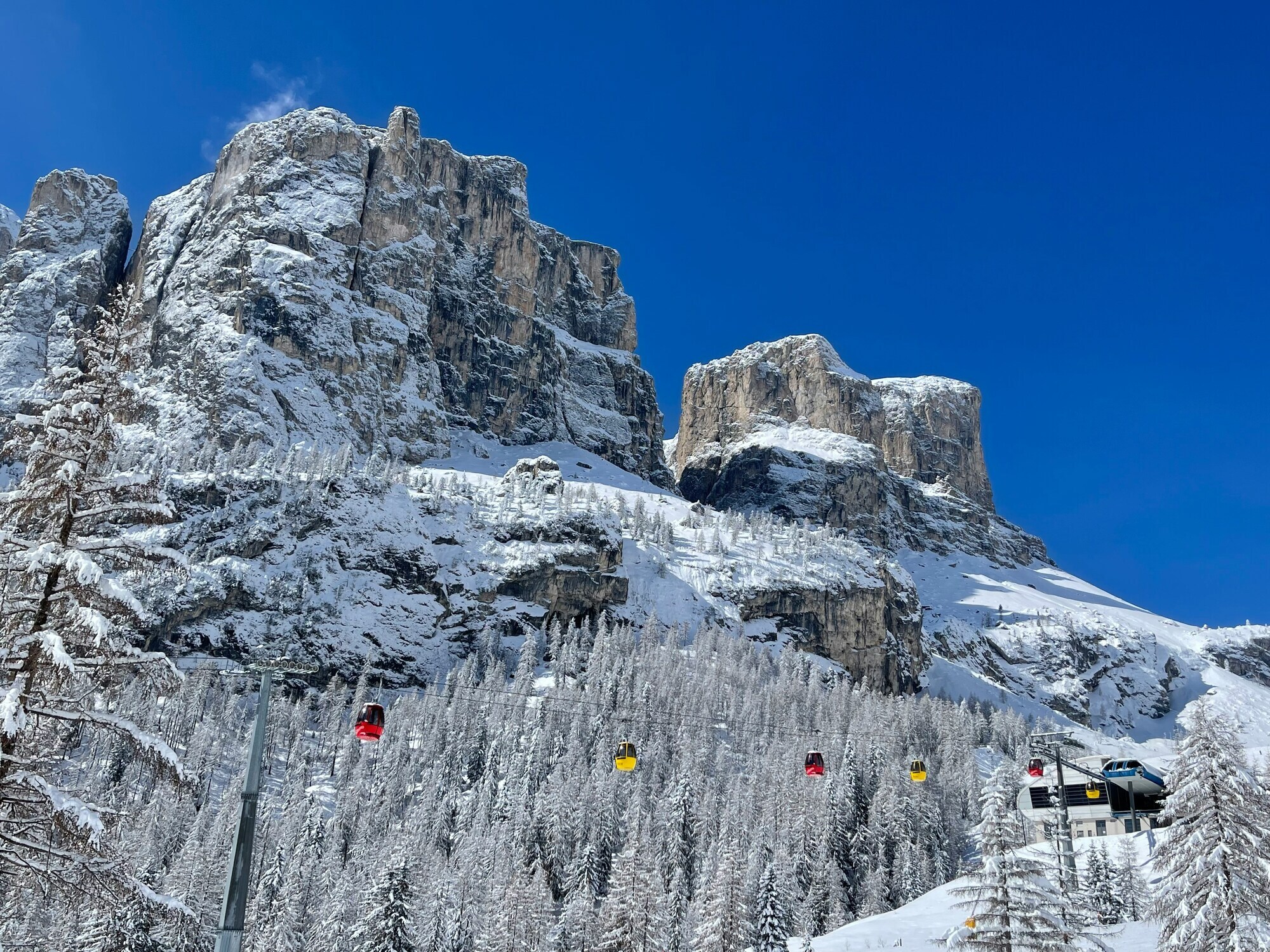 Red and yellow cable car cabins in the middle of a white mountain landscape